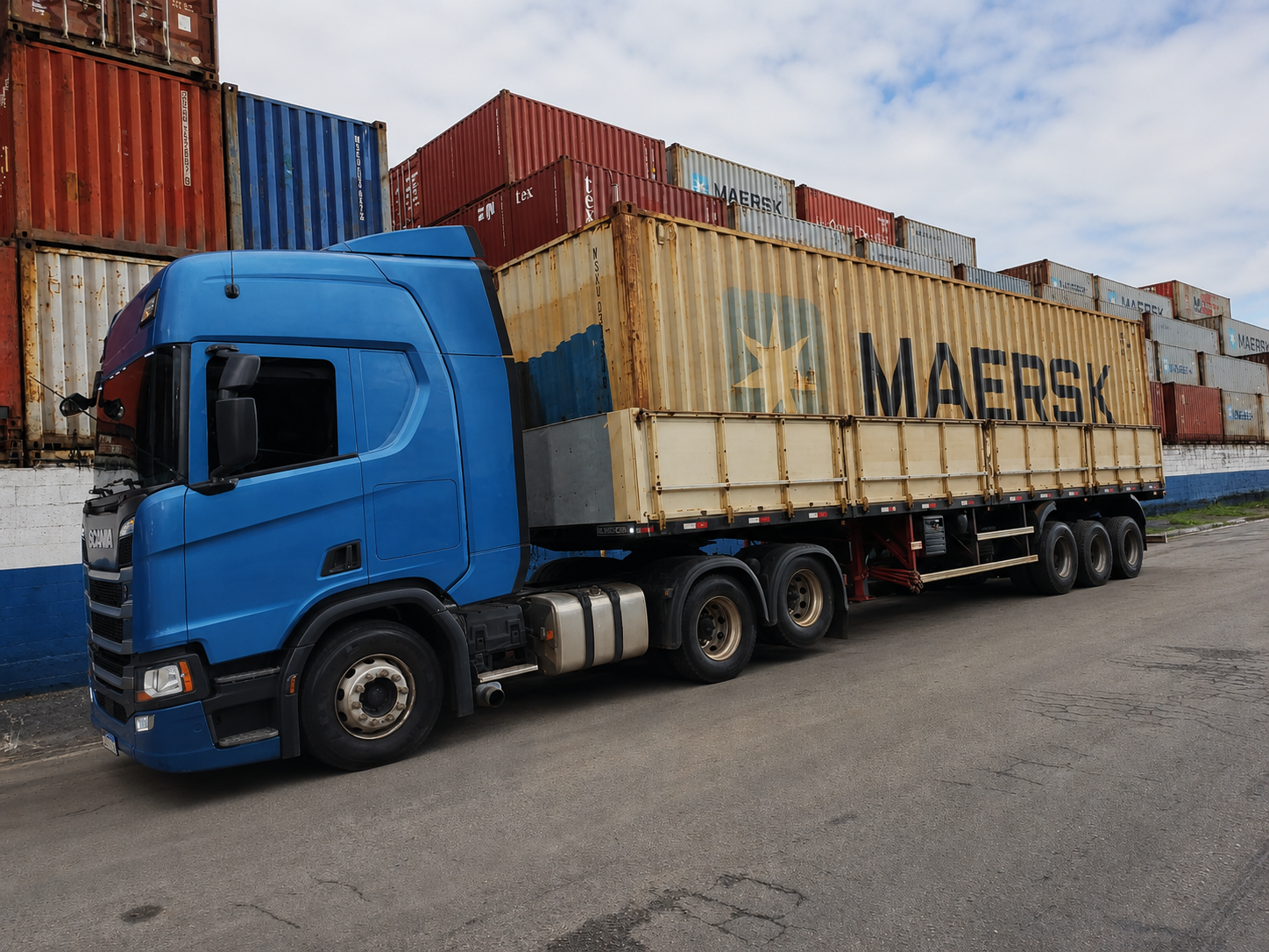 Caminhão realizando o transporte de container marítimo em pátio operacional, com movimentação segura e logística especializada.